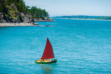 Sailboat on the Coast of Lummi Island, Washington. A sailboat departs Inati Bay on the east coast...