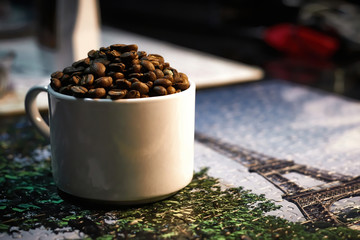 Taza blanca llena de granos de café tostado sobre rompecabezas.
