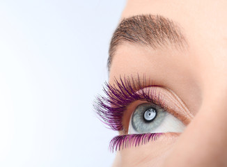 Young woman with beautiful purple eyelashes on light background, closeup. Space for text