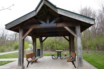 Covered shelter rest stop in public park with benches and picnic table