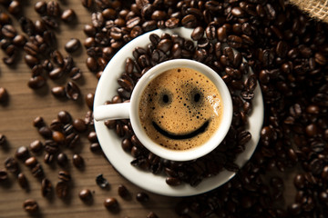 Good morning coffee smile cup and coffee beans on wooden background. Top view.