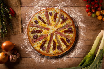 Tasty prosciutto pizza and cooking ingredients tomatoes basil on wood background. Top view prosciutto pizza