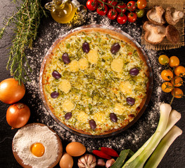 Tasty leek and mushrooms pizza and cooking ingredients tomatoes basil on wood background. Top view of leek pizza