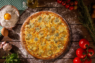 Tasty gorgonzola cheese and zucchini pizza and cooking ingredients tomatoes basil on wood background. Top view gorgonzola cheese and zucchini pizza.