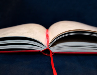 open red-covered book with bookmark ribbon