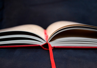 open red-covered book with bookmark ribbon