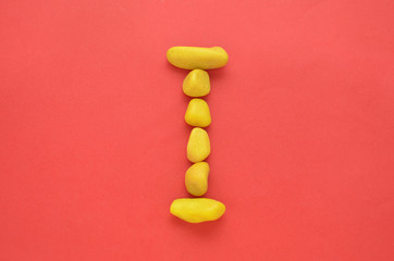 Letter I made of old Yellow pebbles on a red background