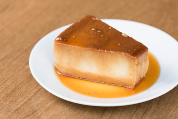un  rico budin bañado con salsa de caramelo en un plato blanco 