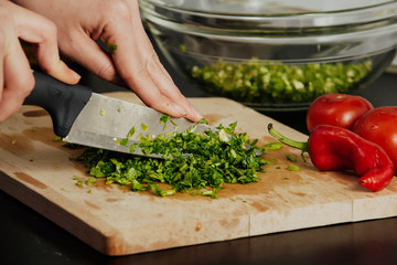 Unknown human hands cooking in kitchen. Woman is busy with vegetable salad. Healthy meal and vegetarian food concept.