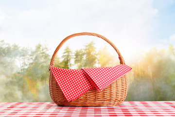 Picnic basket on checkered tablecloth in foggy forest