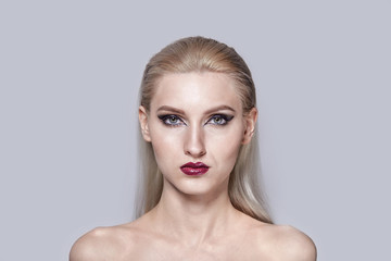 Sexy girl with bare shoulders looks into the frame. Bright make-up.