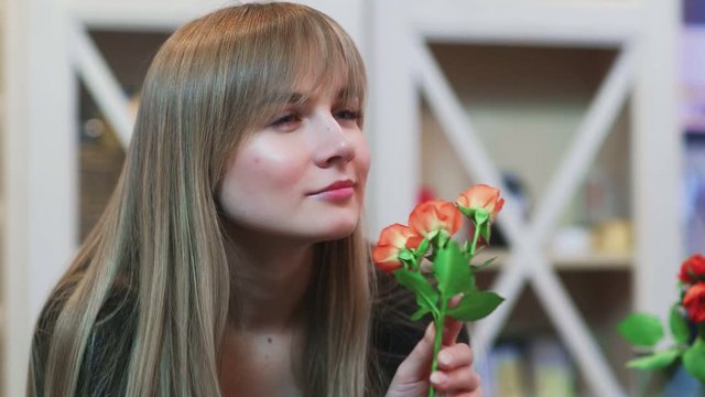 A young woman smelling a flower in a shop