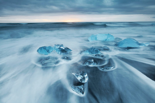 Long exposure of ocean waves and glacial ice chunks on a black sand beach  near Jokulsarlon Glacier Lagoon in southeastern Iceland