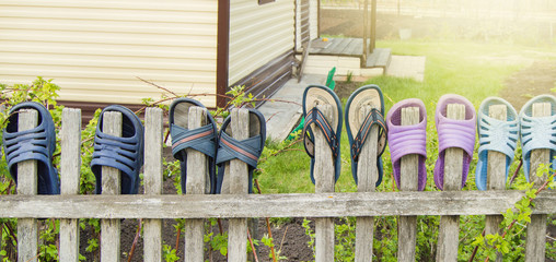 Summer shoes flip flops for a happy friendly family hang on a wooden fence outdoors on a Sunny...