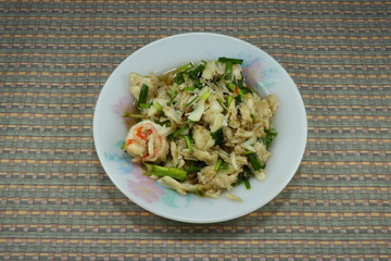 Spicy fried crab meat with peeled fresh shrimp, chilly and local herbal vegetable on the plate. Famous hot and spicy seafood menu in Asia restaurant. 