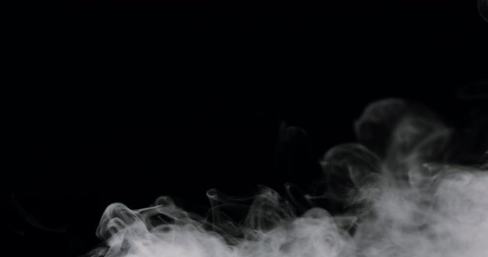 wispy smoke rolling along the bottom of the frame, against a black background.