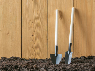Shovels for digging and removing weeds near a wooden fence.
