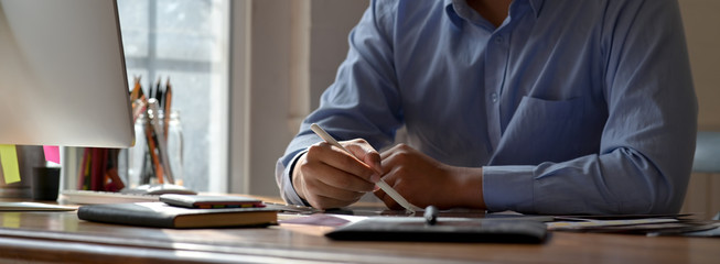 Cropped shot of graphic designer drawing on digital tablet on worktable