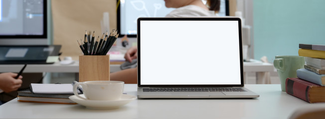 Close up view of office desk with blank screen laptop, coffee cup and stationery