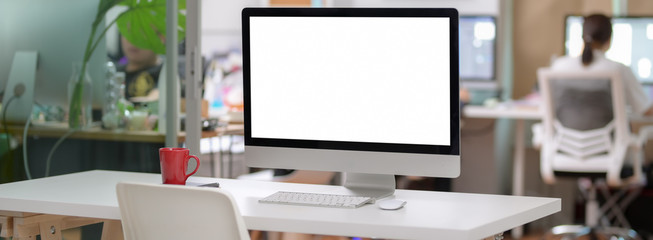 Cropped shot of office desk with blank screen computer and mug in glass partition office