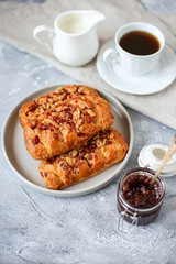 puffs with nuts on light table with a cup of coffee, milk and strawberry jam