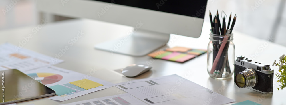 Poster cropped shot of ui developer workspace with computer, stationery and paperwork
