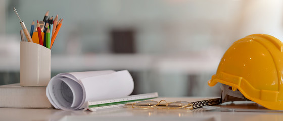 Close up view of engineer worktable with safety helmet, blueprint, measuring tools and other supplies