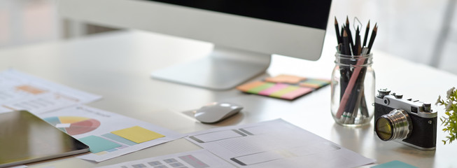 Cropped shot of UI developer workspace with computer, stationery and paperwork - Powered by Adobe