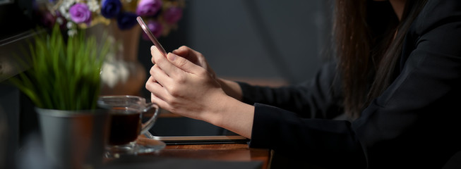 Side view of female freelancer typing text message while sitting at coffee shop