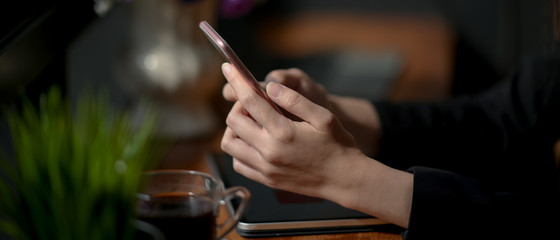 Side view of female freelancer typing on smartphone to contact her customer