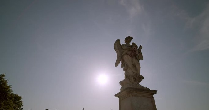 Walking past one of the statues along bridge leading to the famous Castel Sant' Angelo landmark located in Vatican City Rome Italy