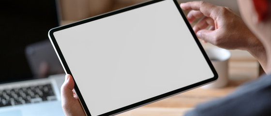 Close up view of a man holding blank screen tablet at home office