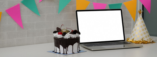 Online birthday party concept with blank screen laptop, cake, decoration
