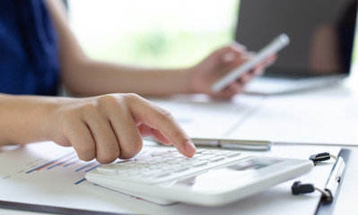 Accounting businessmen are calculating income-expenditure and analyzing real estate investment data, She works on a desk has graphs and calculators with laptop, Financial and tax systems concept.