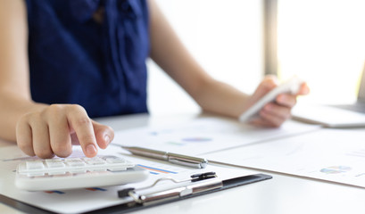 Accounting businessmen are calculating income-expenditure and analyzing real estate investment data, She works on a desk has graphs and calculators with laptop, Financial and tax systems concept.