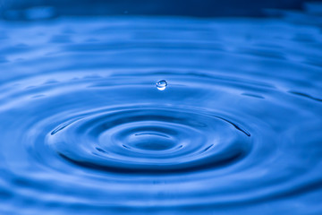 Naklejka na ściany i meble Water drop close up of in a blurred blue background