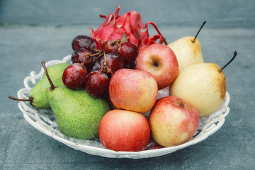 fresh fruits on white basket, dragon fruit, apple, pears and grapes