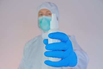 Antiseptic. Hand disinfection concept.Doctor in a protective mask, glasses and a suit with a bottle of antiseptic on a light background. Protection against germs. The rules of hygiene and health.