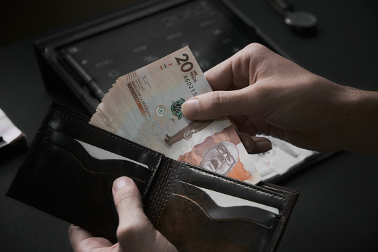 Man's Hands Piking Up 20000 Colombian Pesos Bill From A Dark Wallet On A Office Background