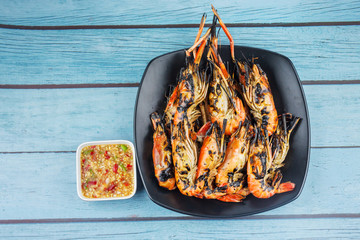 Many fresh river prawns grilled with seafood sauce Placed on blue wood background , weighing 1 kg