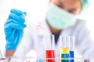  Female researchers are experimenting with pipette dropping a sample into a test tube in an experiment research in laboratory.