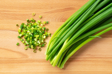 Chopped green onions placed on a wooden board.