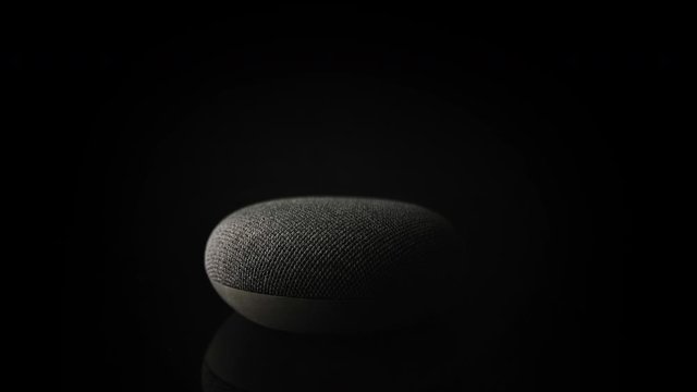 Product shot of voice-activated smart home speaker isolated on a black background.