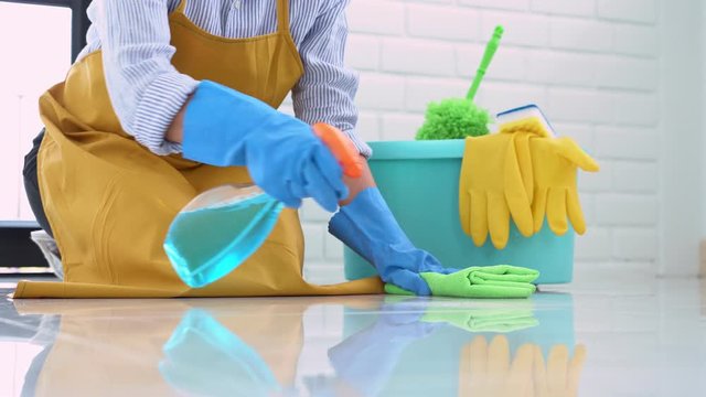 4k video of Housekeeper maid wearing rubber gloves with cloth cleaning or applying floor care and cleaners at home, housework and housekeeping concept.