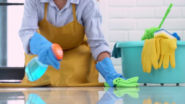 4k video of Housekeeper maid wearing rubber gloves with cloth cleaning or applying floor care and cleaners at home, housework and housekeeping concept.