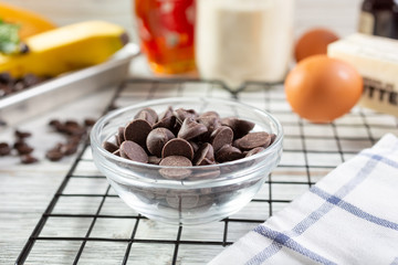 A view of a glass bowl filled with semi sweet chocolate morsels, in a still life setting.