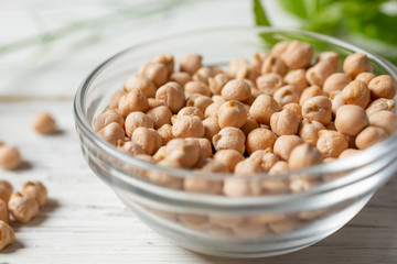 A closeup view of a glass bowl filled with dried chickpeas.