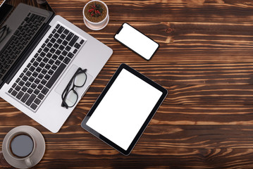 Laptop, smartphone, tablet and coffee cup with financial documents on wooden table