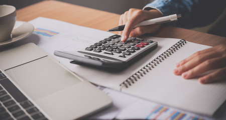 The accountant's hand is using the calculator. For cost analysis Profit and loss and tax...