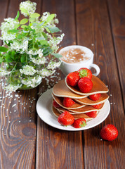 Delicious, just baked pancakes with strawberries and a cup of coffee
